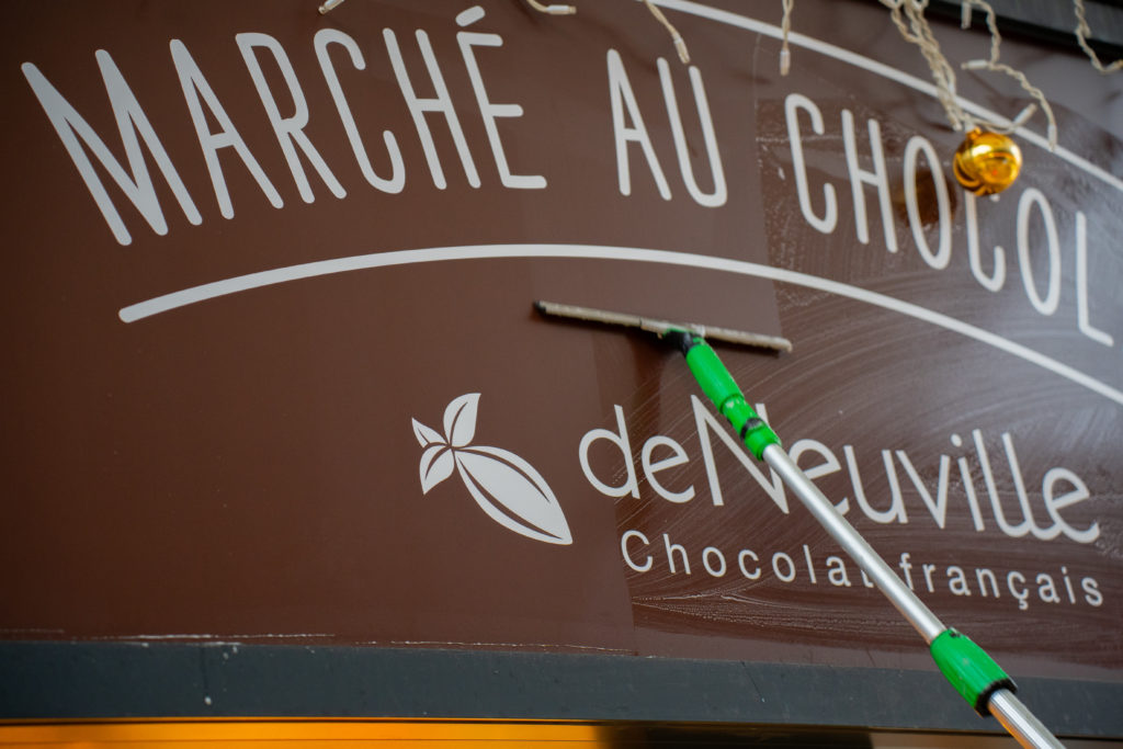 Photo de la vitrine commerciale du marché au chocolat de Neuville lors de son nettoyage par VALO'Propreté.